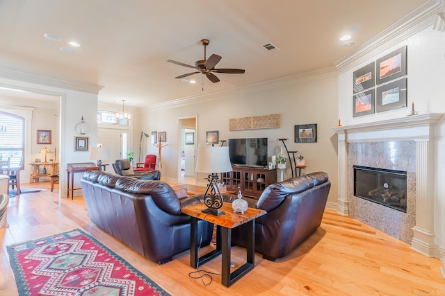 living room with a fireplace, light wood-type flooring, ceiling fan, and ornamental molding