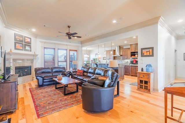 living room featuring ceiling fan, light wood-type flooring, and ornamental molding