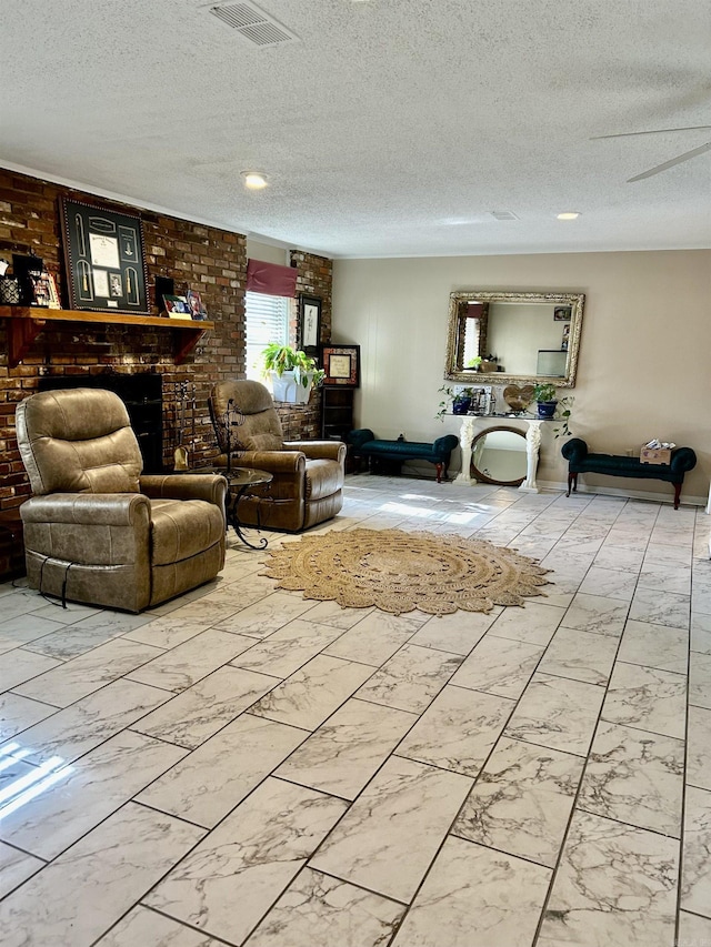 living room with ceiling fan, brick wall, a textured ceiling, and a brick fireplace