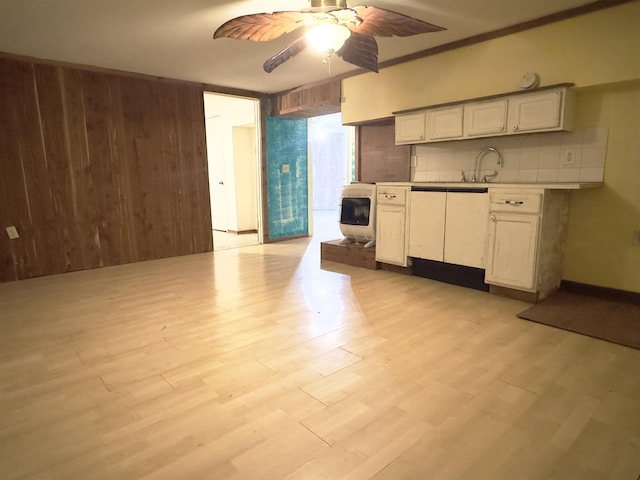 kitchen with light wood finished floors, tasteful backsplash, light countertops, ceiling fan, and wooden walls