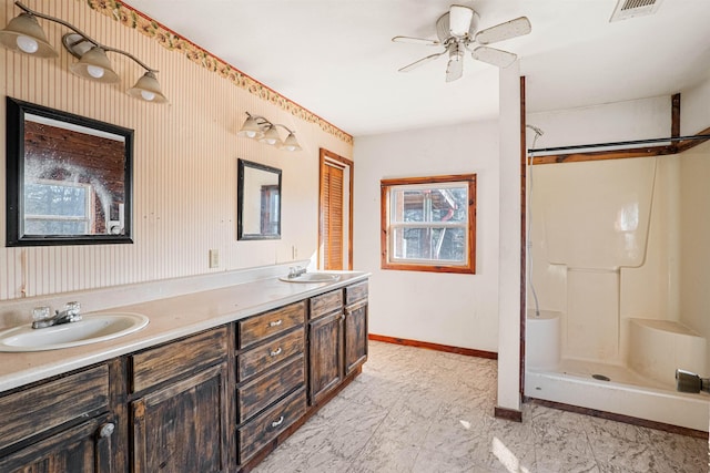 full bath with a shower, double vanity, a sink, and baseboards