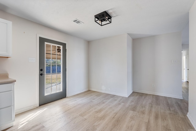 spare room with light wood-type flooring and a textured ceiling