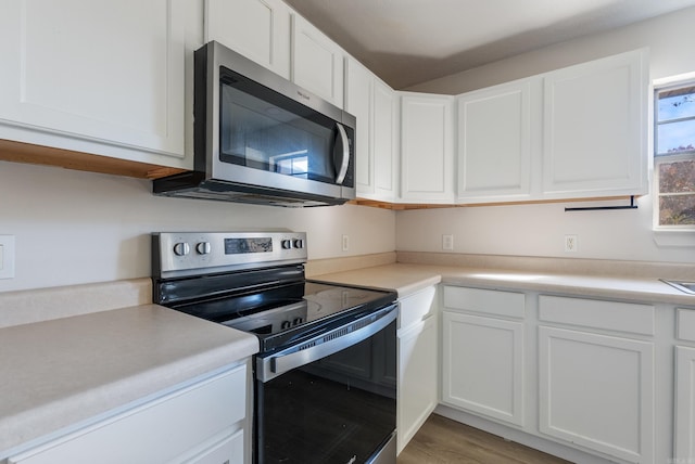 kitchen with white cabinets, appliances with stainless steel finishes, and light wood-type flooring