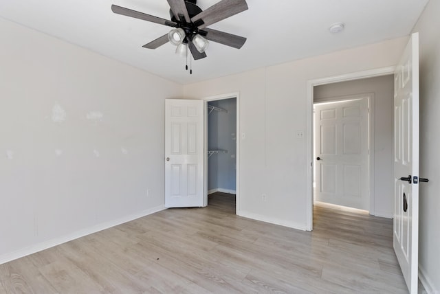 unfurnished bedroom with a closet, a walk in closet, light hardwood / wood-style floors, and ceiling fan