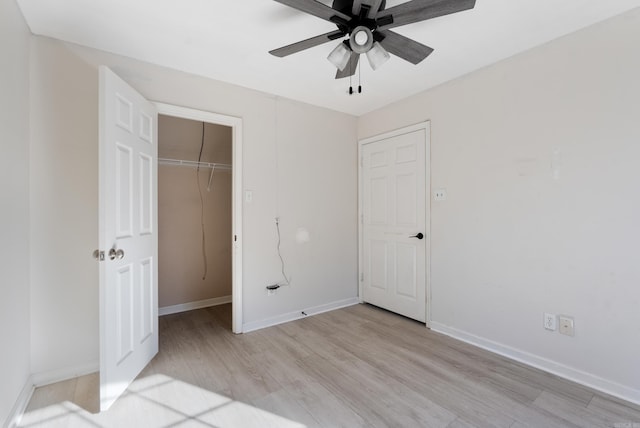 unfurnished bedroom with ceiling fan, a closet, light hardwood / wood-style floors, and a spacious closet