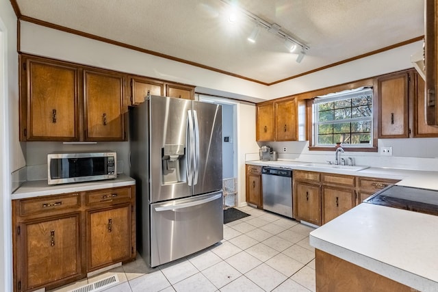 kitchen with a textured ceiling, stainless steel appliances, crown molding, sink, and light tile patterned floors