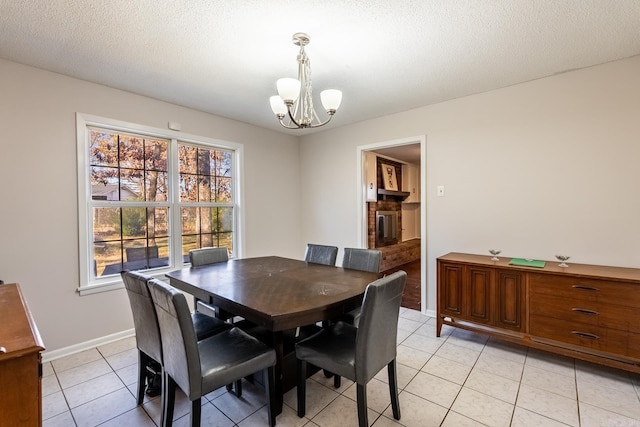 tiled dining area with a fireplace, a textured ceiling, and a notable chandelier