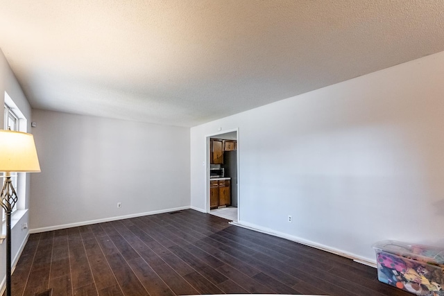 spare room featuring a textured ceiling and dark hardwood / wood-style floors