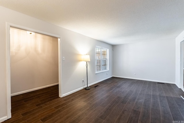 unfurnished room with a textured ceiling and dark wood-type flooring