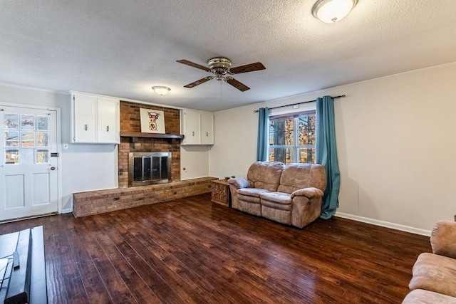 living room featuring a textured ceiling, ceiling fan, a fireplace, and dark hardwood / wood-style floors