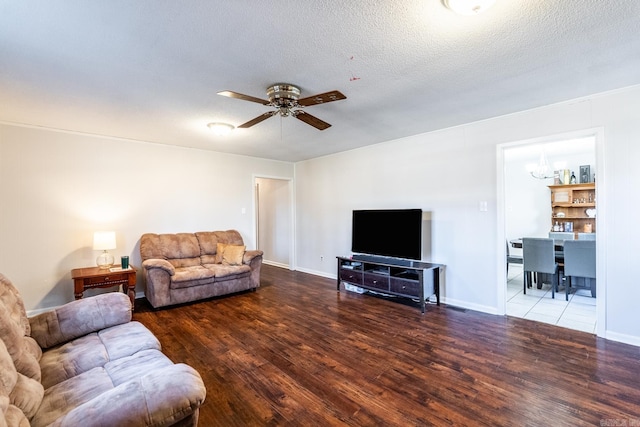 living room featuring hardwood / wood-style floors, ceiling fan with notable chandelier, and a textured ceiling