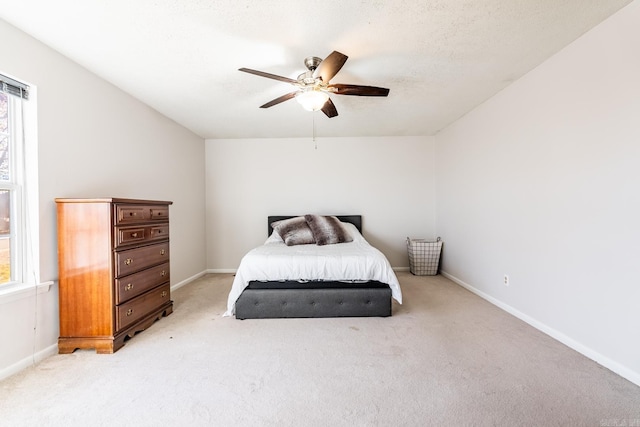 carpeted bedroom featuring ceiling fan and a textured ceiling