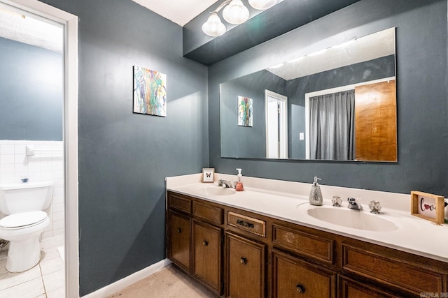 bathroom with tile patterned flooring, vanity, toilet, and tile walls