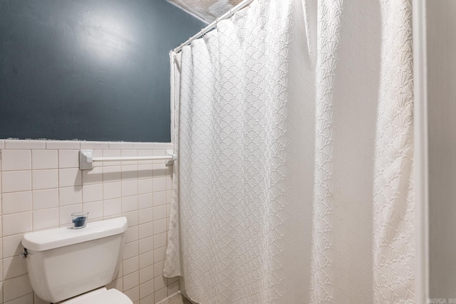 bathroom with toilet and tile walls