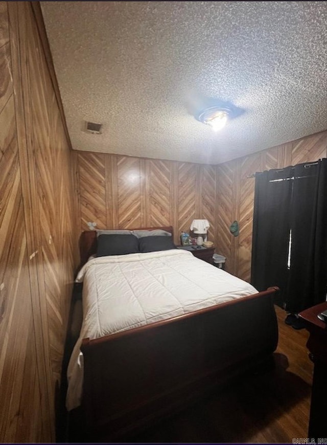 bedroom with wood walls and a textured ceiling