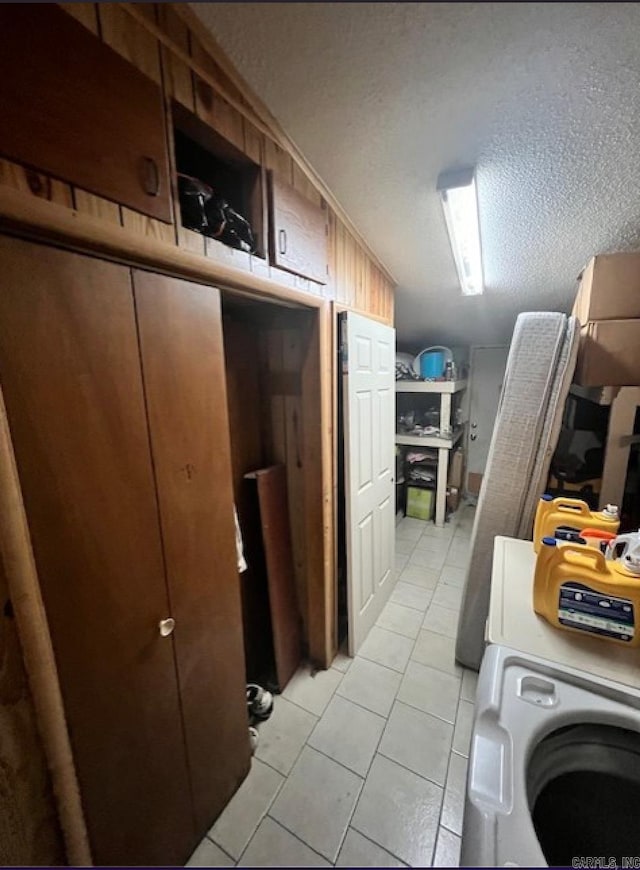 clothes washing area with light tile patterned flooring, a textured ceiling, and washer / dryer