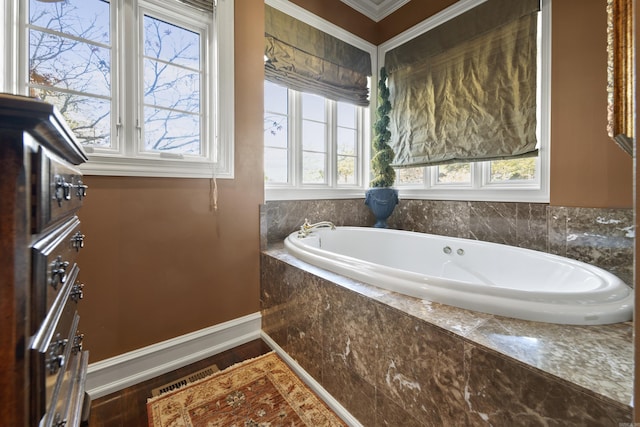 bathroom with tiled tub, a healthy amount of sunlight, and ornamental molding