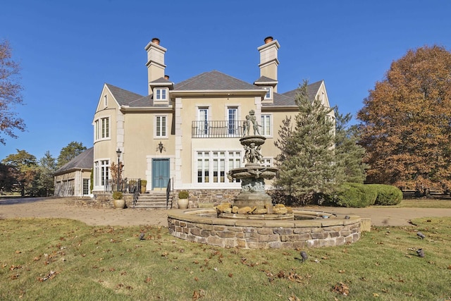 rear view of house with a yard and a balcony