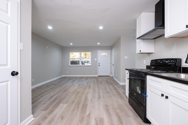 kitchen with light wood-type flooring, sink, wall chimney range hood, white cabinets, and black / electric stove