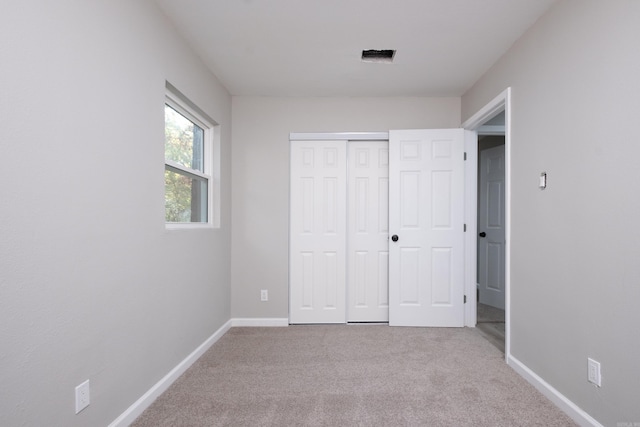 unfurnished bedroom with light colored carpet and a closet