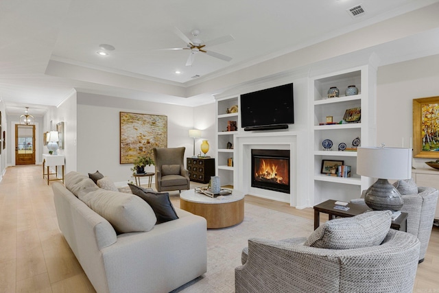 living room with built in shelves, ceiling fan, light hardwood / wood-style floors, and ornamental molding