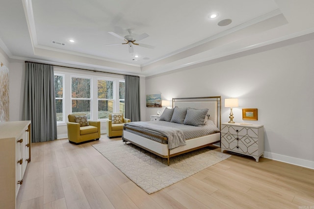 bedroom with ceiling fan, light hardwood / wood-style floors, a raised ceiling, and ornamental molding