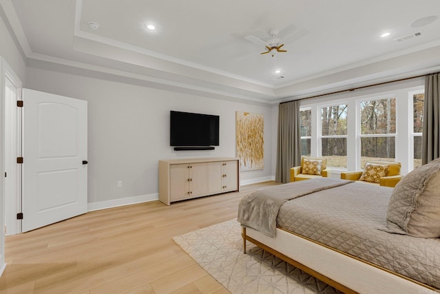 bedroom featuring ceiling fan, light hardwood / wood-style floors, a raised ceiling, and ornamental molding