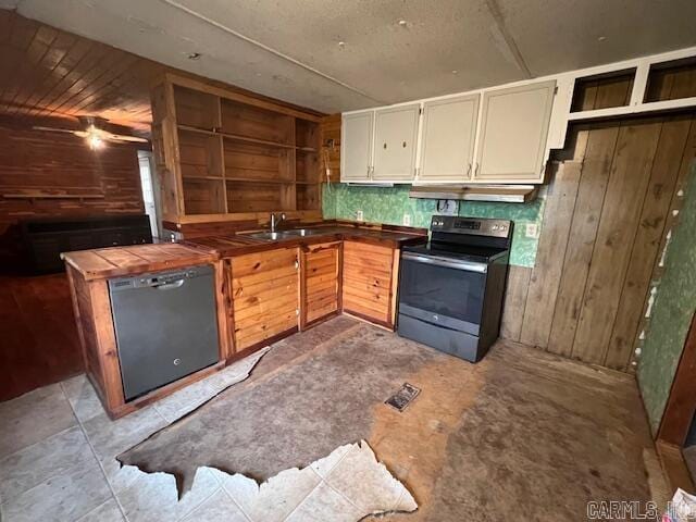 kitchen with black appliances, wood walls, and sink