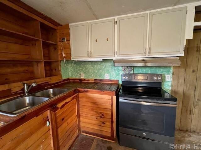 kitchen featuring white cabinetry, stainless steel range with electric stovetop, wooden walls, and sink