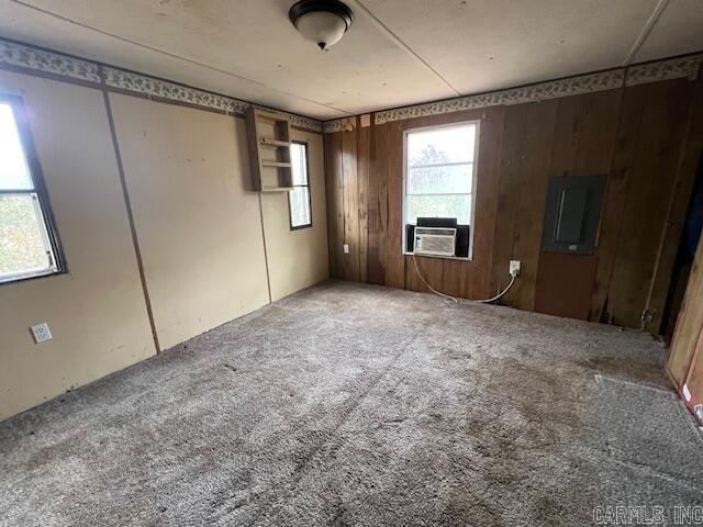 spare room featuring carpet floors, electric panel, cooling unit, and wooden walls