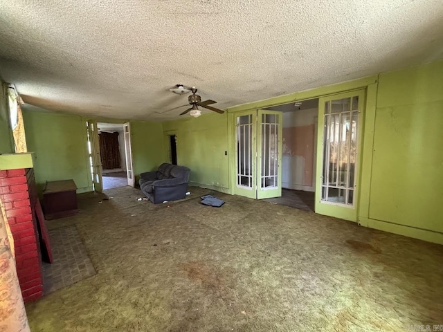 unfurnished living room with carpet floors, a ceiling fan, a textured ceiling, and french doors