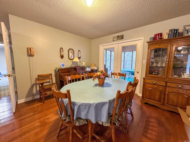 dining space featuring a textured ceiling, french doors, and dark hardwood / wood-style floors