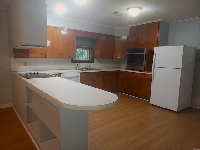 kitchen featuring stainless steel appliances, kitchen peninsula, light wood-type flooring, a textured ceiling, and ornamental molding