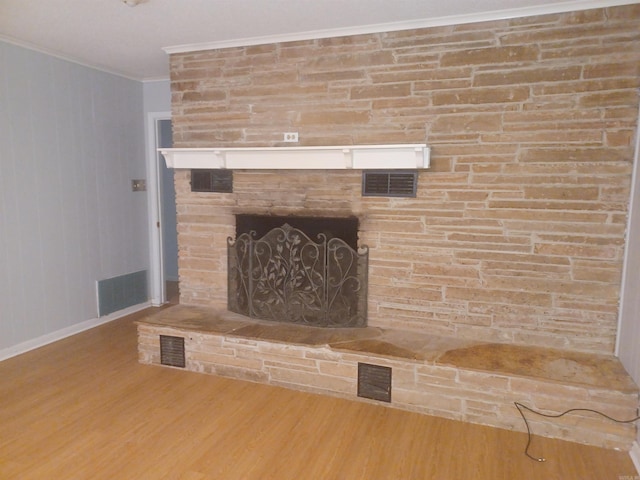 interior details with wood-type flooring, a stone fireplace, and crown molding