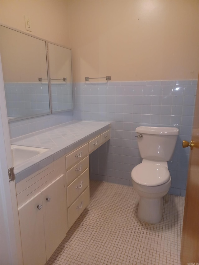 bathroom with tile patterned floors, vanity, toilet, and tile walls