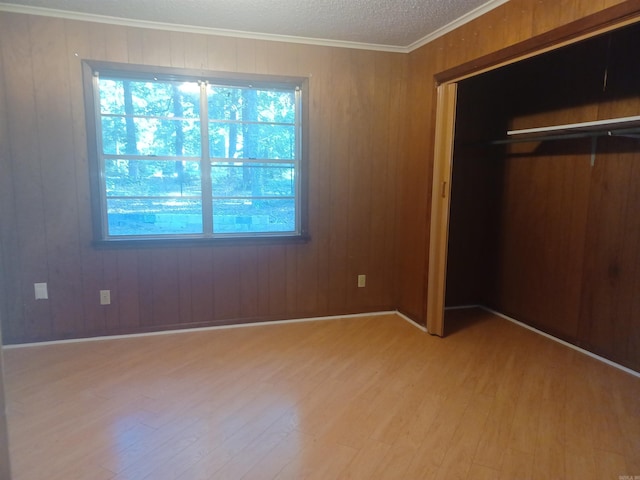 unfurnished bedroom featuring light wood-type flooring and wood walls