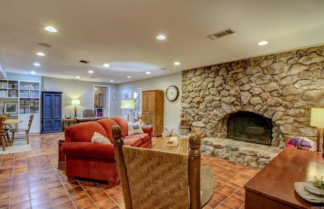 tiled living room with a stone fireplace