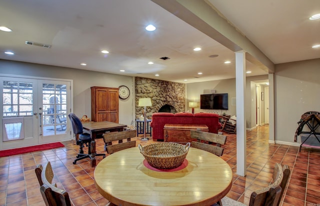 tiled dining area featuring a stone fireplace and french doors