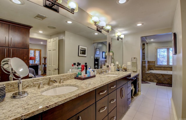 bathroom featuring tile patterned flooring, vanity, and a relaxing tiled tub