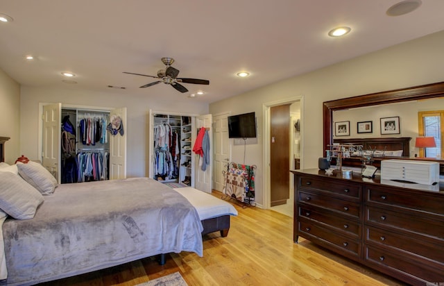 bedroom featuring multiple closets, ceiling fan, and light hardwood / wood-style floors