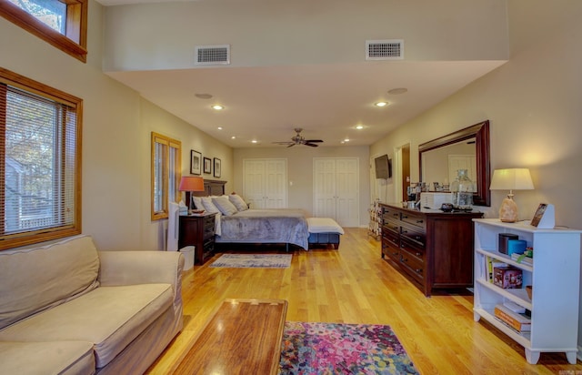 bedroom featuring ceiling fan, light hardwood / wood-style floors, and two closets