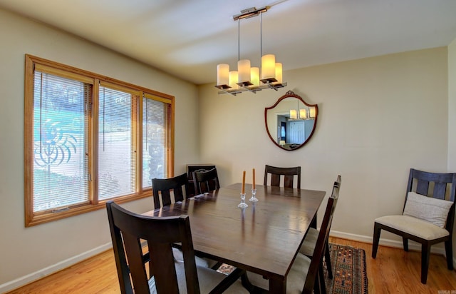 dining area with light hardwood / wood-style floors and a notable chandelier