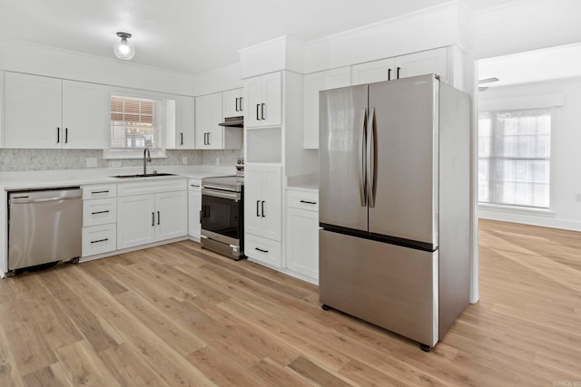 kitchen featuring sink, light hardwood / wood-style flooring, tasteful backsplash, white cabinetry, and stainless steel appliances