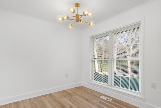 unfurnished room with hardwood / wood-style flooring, ornamental molding, and an inviting chandelier