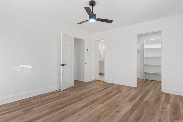 unfurnished bedroom with light wood-type flooring, a spacious closet, and ceiling fan