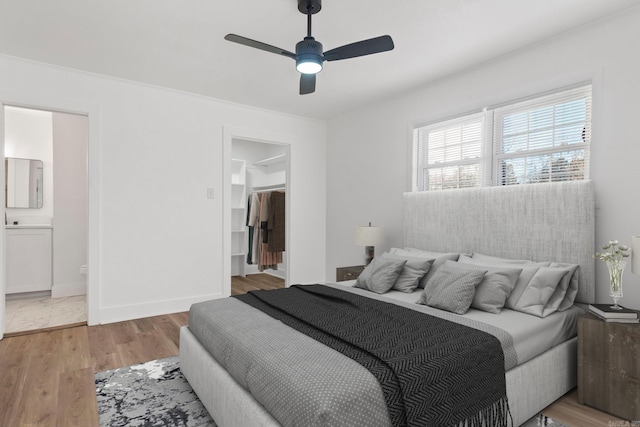 bedroom featuring light hardwood / wood-style flooring, ensuite bath, and ceiling fan