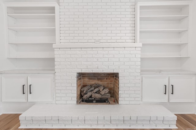 details featuring a fireplace, built in shelves, and hardwood / wood-style flooring