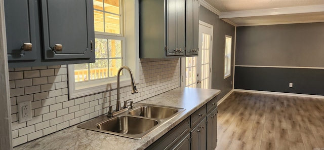 kitchen with light wood-type flooring, backsplash, ornamental molding, and sink