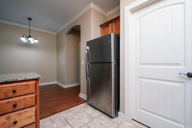 kitchen featuring hanging light fixtures, light hardwood / wood-style flooring, ornamental molding, a notable chandelier, and stainless steel refrigerator