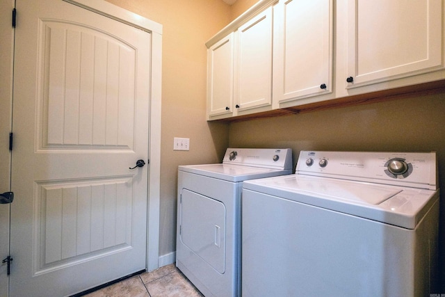 laundry room with washer and clothes dryer, cabinets, and light tile patterned floors